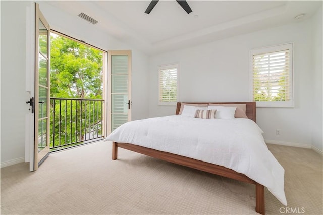 bedroom with access to outside, light carpet, baseboards, a tray ceiling, and visible vents