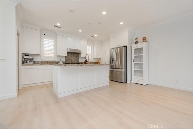 kitchen featuring ornamental molding, white cabinetry, under cabinet range hood, stainless steel fridge with ice dispenser, and light wood-style flooring