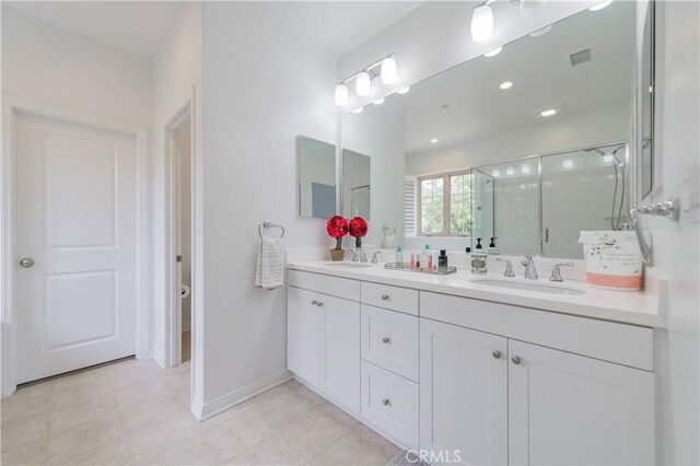 bathroom with a sink, double vanity, baseboards, a shower stall, and visible vents