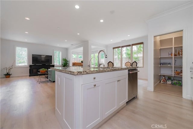 kitchen with a sink, light stone counters, plenty of natural light, and stainless steel dishwasher
