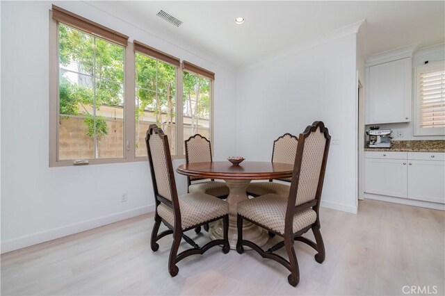 dining room featuring visible vents, light wood finished floors, crown molding, and baseboards