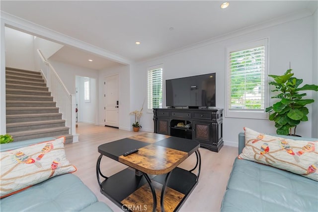 living room with baseboards, ornamental molding, light wood finished floors, and stairway