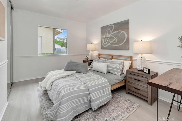 bedroom with baseboards, ornamental molding, and wood finished floors