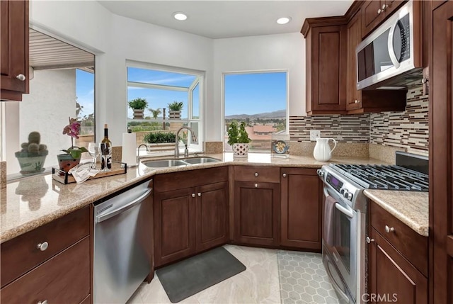 kitchen with recessed lighting, tasteful backsplash, light stone counters, a sink, and stainless steel appliances