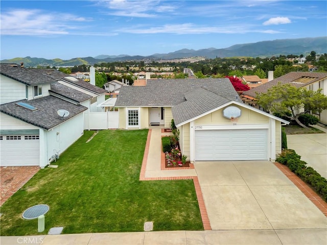 view of front of house with a front lawn, fence, roof with shingles, concrete driveway, and a mountain view