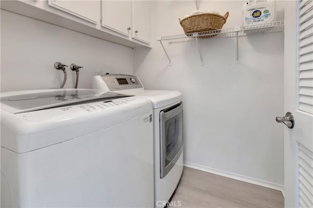 clothes washing area with light wood-style floors, baseboards, cabinet space, and washing machine and dryer