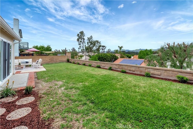 view of yard featuring a patio, a fenced backyard, and a mountain view
