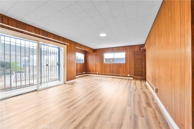 20908 New Hampshire Ave, Torrance, CA 90502 - unfurnished living room with baseboards, light wood-style flooring, and wood walls