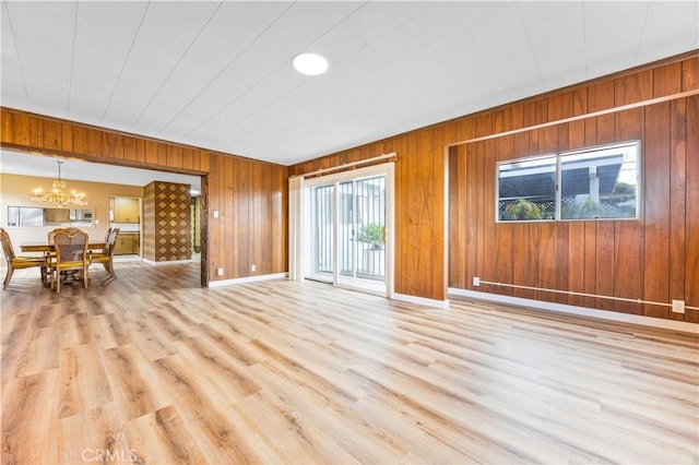 20908 New Hampshire Ave, Torrance, CA 90502 - living area with a chandelier, wood walls, light wood-type flooring, and baseboards