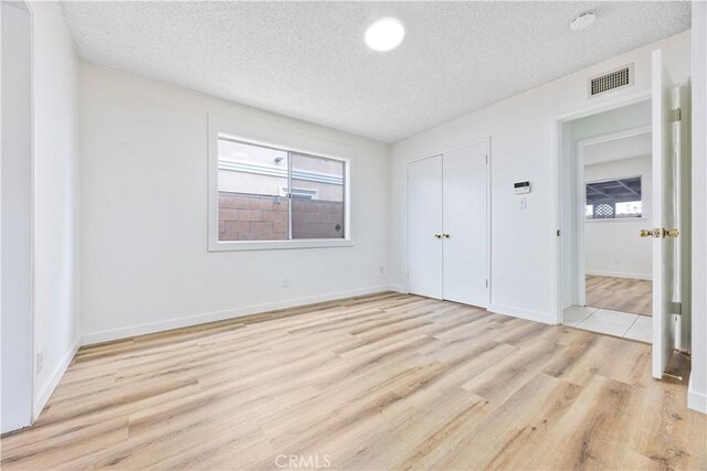 20908 New Hampshire Ave, Torrance, CA 90502 - unfurnished bedroom featuring a textured ceiling, light wood finished floors, a closet, multiple windows, and baseboards