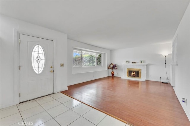 entryway with a glass covered fireplace, baseboards, and light wood finished floors