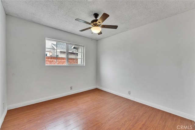 empty room with baseboards, a textured ceiling, ceiling fan, and wood finished floors