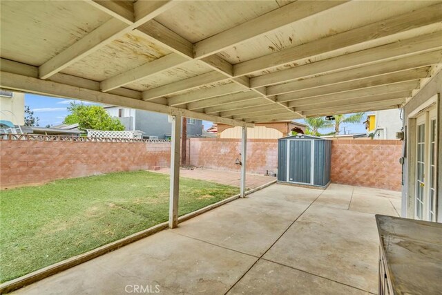 view of patio / terrace featuring an outdoor structure, a fenced backyard, and a storage shed