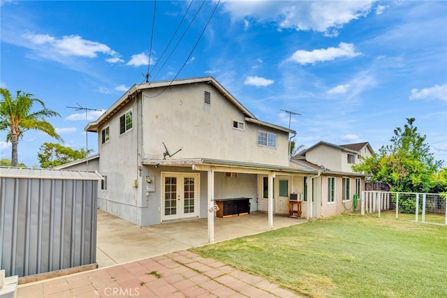 rear view of property with french doors, a patio area, a fenced backyard, a yard, and stucco siding