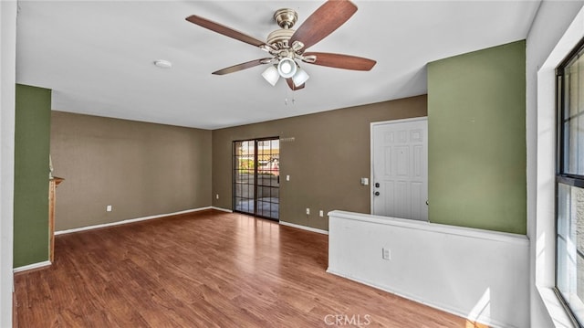 empty room with baseboards, ceiling fan, and wood finished floors