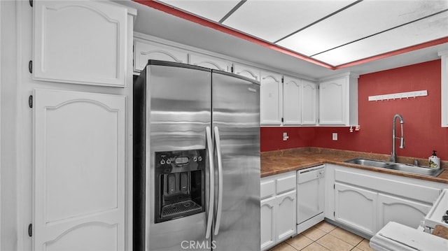 kitchen featuring dark countertops, stainless steel fridge, white cabinets, a sink, and dishwasher