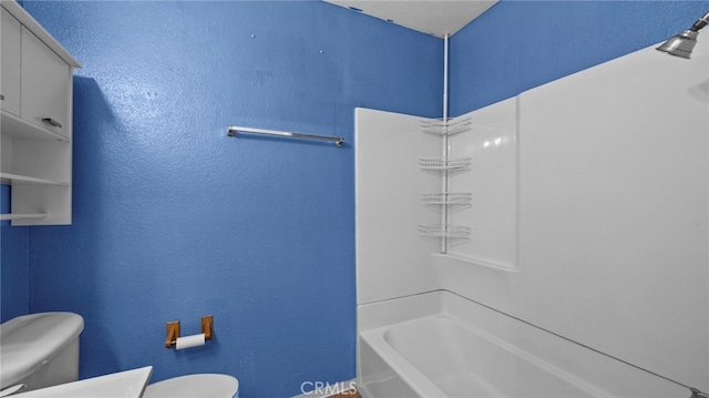 bathroom featuring toilet, baseboards, and shower / washtub combination