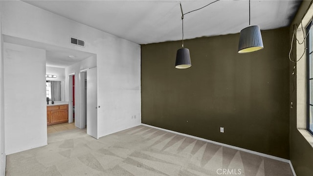 spare room featuring visible vents and light carpet