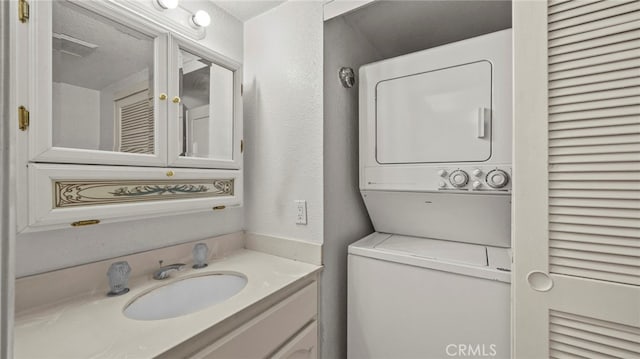 bathroom with vanity, stacked washer and dryer, and a textured wall