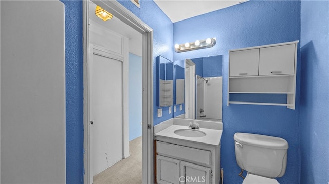 bathroom featuring vanity, a textured wall, and toilet