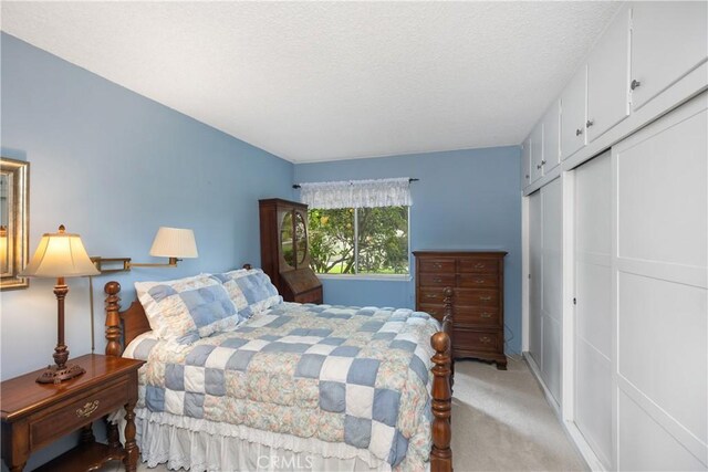 124 Via Estrada Unit D, Laguna Woods, CA 92637 - bedroom featuring a textured ceiling, a closet, and light carpet