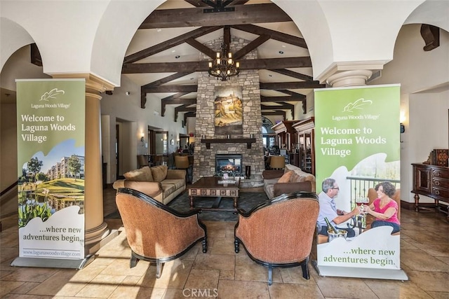 124 Via Estrada Unit D, Laguna Woods, CA 92637 - living area with an inviting chandelier, a stone fireplace, stone tile floors, beam ceiling, and ornate columns