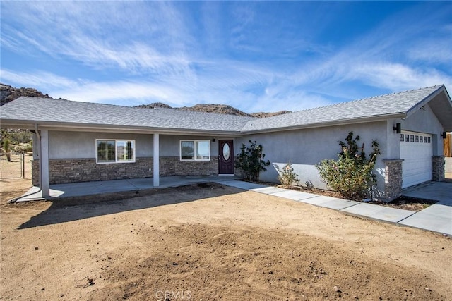 ranch-style home featuring stucco siding, a shingled roof, stone siding, and a garage