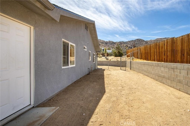 view of property exterior with a mountain view, stucco siding, and a fenced backyard