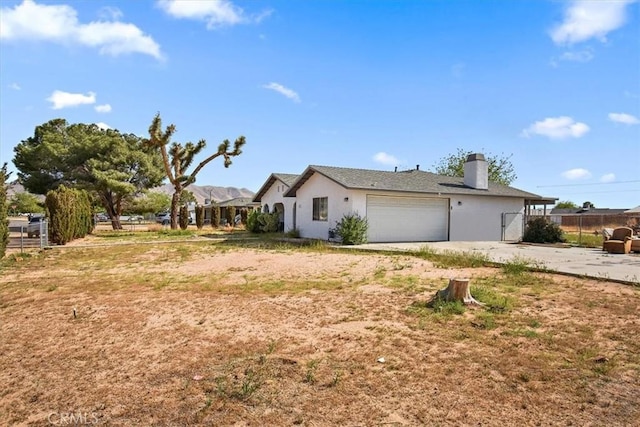 view of home's exterior featuring driveway, a chimney, a garage, and fence