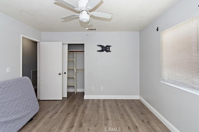 unfurnished bedroom featuring a closet, visible vents, wood finished floors, and baseboards
