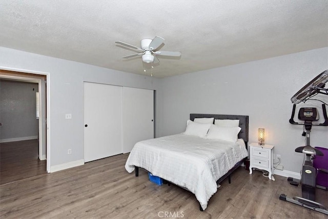 bedroom featuring baseboards, wood finished floors, ceiling fan, and a closet