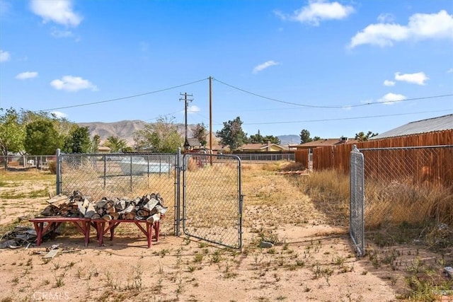 view of yard featuring a mountain view, a gate, and fence