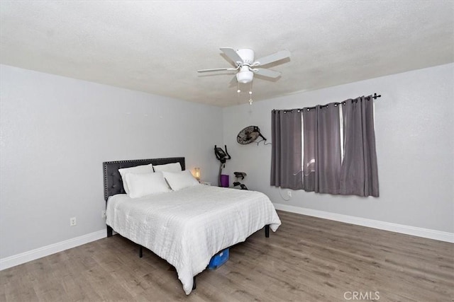 bedroom featuring baseboards, wood finished floors, and a ceiling fan