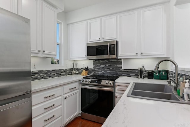 kitchen featuring tasteful backsplash, white cabinetry, stainless steel appliances, and a sink