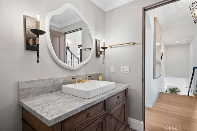 bathroom with wood finished floors, ornamental molding, and vanity