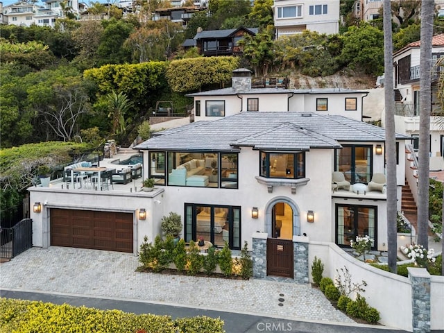 view of front of property with stucco siding, decorative driveway, a balcony, and fence private yard