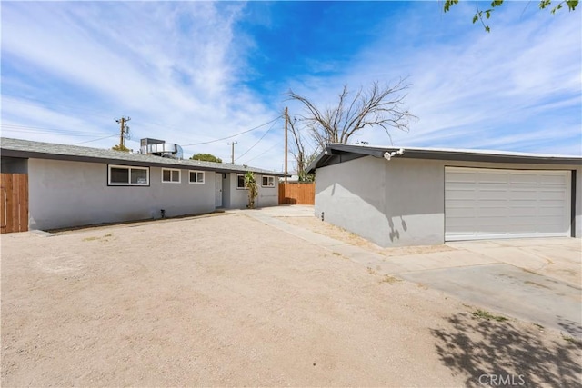 exterior space featuring central AC, fence, stucco siding, and concrete driveway