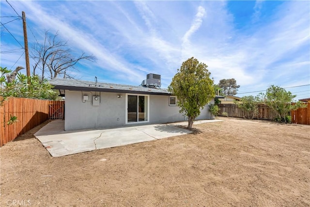 back of house featuring stucco siding, a patio area, central AC, and a fenced backyard