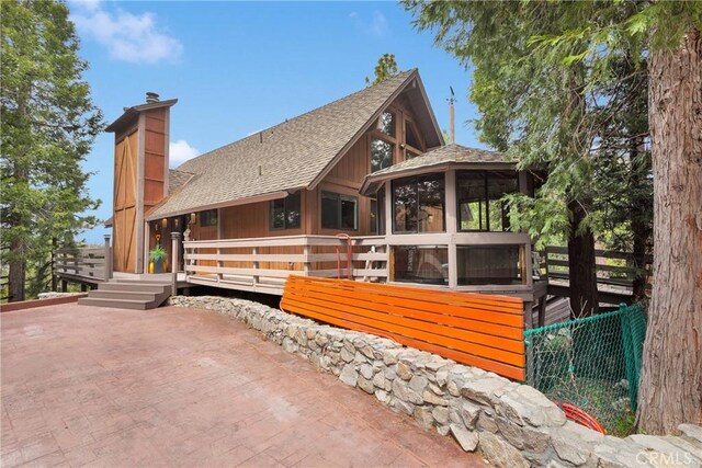 825 Grass Valley Rd, Lake Arrowhead, CA 92352 - view of home's exterior featuring a chimney, a wooden deck, a sunroom, a patio area, and roof with shingles