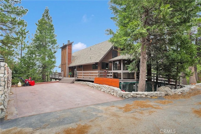 825 Grass Valley Rd, Lake Arrowhead, CA 92352 - view of property exterior with a sunroom, roof with shingles, a wooden deck, and a chimney