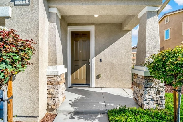 property entrance featuring stucco siding and stone siding