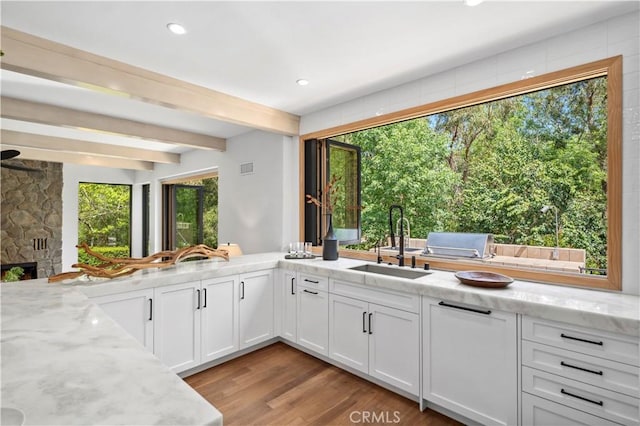 1935 Maverick Ln, North Tustin, CA 92705 - kitchen with light stone counters, white cabinets, a sink, beam ceiling, and light wood-type flooring
