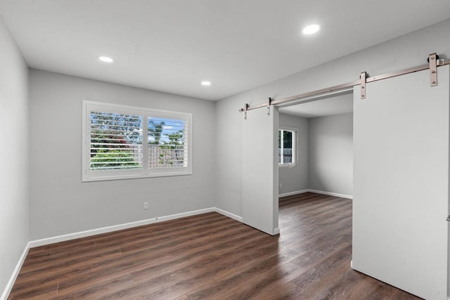 3185 Monroe St, Carlsbad, CA 92008 - empty room featuring a barn door, healthy amount of natural light, dark wood-type flooring, recessed lighting, and baseboards