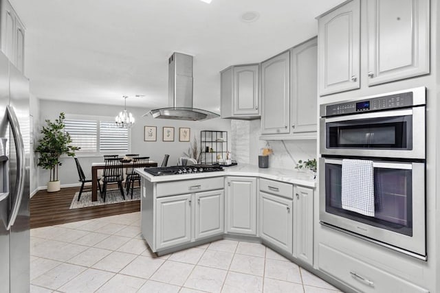 3185 Monroe St, Carlsbad, CA 92008 - kitchen featuring appliances with stainless steel finishes, island range hood, light tile patterned floors, light countertops, and a peninsula