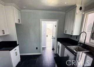 kitchen featuring white cabinets, dark countertops, baseboards, pendant lighting, and crown molding