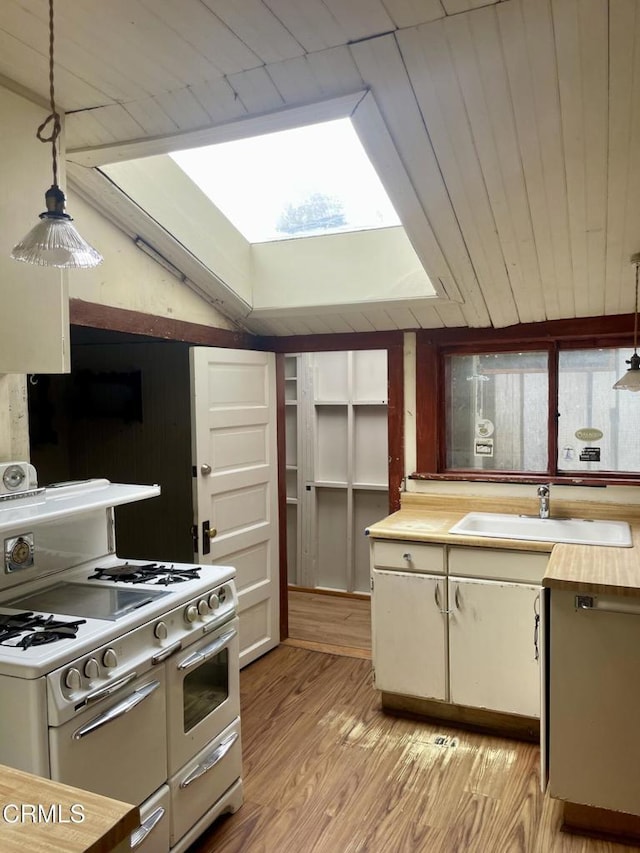 kitchen featuring a sink, light wood-style floors, wooden counters, pendant lighting, and double oven range