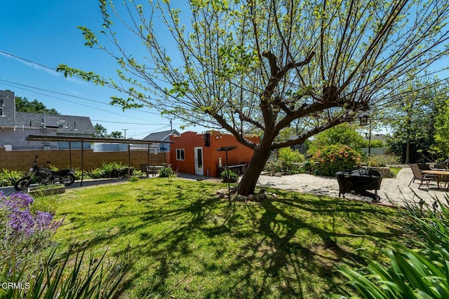 view of yard with fence, a fire pit, and a patio area