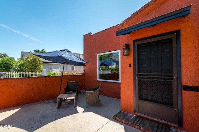 doorway to property featuring fence, stucco siding, and a patio area