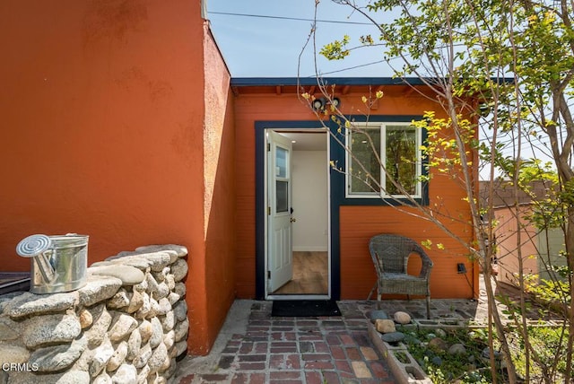 entrance to property featuring stucco siding and fence