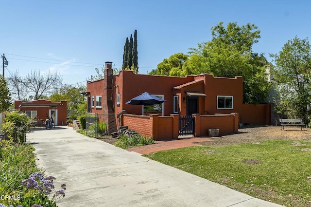 view of front of property with a front lawn, a fenced front yard, a gate, driveway, and stucco siding